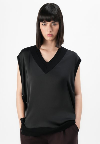 Top sans manches noir avec un col en V, fabriqué à partir d'un tissu lisse. Présente des bords côtelés et des boutons décoratifs sur le côté.