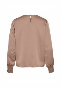 Béžová blúzka s dlhými rukávmi, so smockovanými manžetami a malým otvorom v zadnom výstrihu.