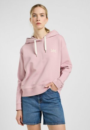 Felpa rosa con una vestibilità comoda, cappuccio con cordino, polsini e orlo a coste; presenta un logo ricamato sul petto. Abbinata a pantaloni shorts di denim.