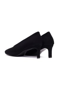 Escarpins en suede noir avec un bout pointu et un talon fin. Texture lisse sans matériel ou motifs visibles.