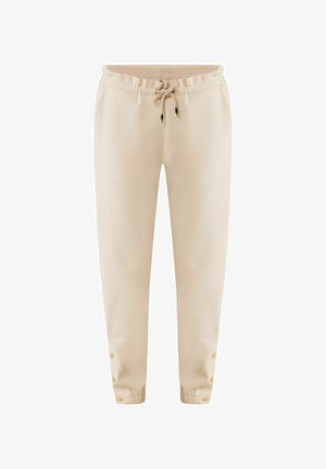 Pantalones jogger beige, hechos de un tejido suave, que cuentan con una cintura elástica con cordón y detalles de botones a presión en los puños del tobillo.