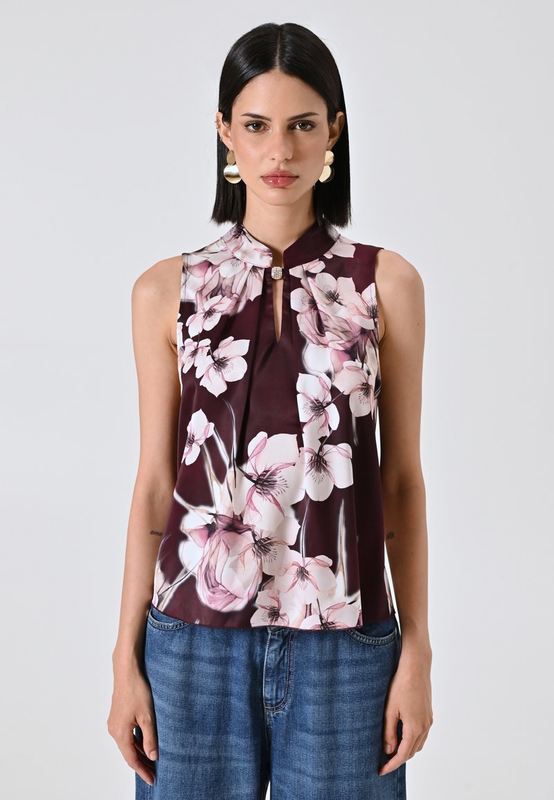 Blusa senza maniche con motivo floreale in un profondo bordeaux, caratterizzata da un collo a chiave e un tessuto morbido con fiori rosa e bianchi.