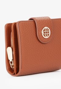 Portafoglio in pelle marrone con texture a pallini, dotato di un bottone logo dorato e di una tasca con zip. Design compatto con chiusura sicura.