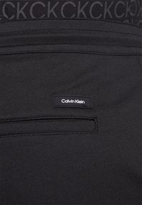 Calvin Klein COMFORT LOGO TAPE PANT - Calças de fato de treino - black