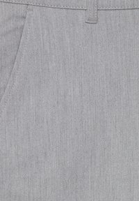 Ljust grått tyg med en texturerad yta, med en ficka på vänster sida och subtila sömdetaljer, lämplig för avslappnad klädsel.