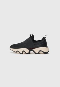 Sorte slip-on sneakers med bred elastisk stropp, teksturert stoffoverdel og tykk beige såle med svart bølget mønster samt pull-tabs på hæl og tå.