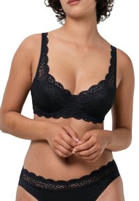 Svart spets-bh med scalloped kanter, underwire stöd och justerbara axelremmar. Matchas med svarta spets-trosor.