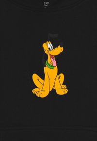 Felpa nera con un grafiche di un cane di cartone giallo con un collare verde, seduto con la lingua di fuori, espressione giocosa.