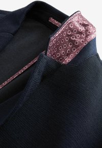 Granatowy sweter z fakturowanej tkaniny, z kontrastową bordową kołnierzem w kwiatowy wzór oraz wykończonym dekoltem.
