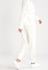 Ensemble sweat-shirt blanc oversize et pantalon de jogging, avec une coupe décontractée, un tissu doux, des poignets côtelés et des détails de design sans coutures.