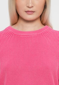 Sweater de malha em rosa com decote redondo. Apresenta um padrão texturizado e um acabamento suave, realçando a cor vibrante.