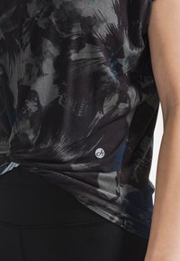 Kurzärmliges Hemd in dunklen Farben mit abstrakten Mustern. Hergestellt aus weichem Stoff, mit kleinem Logo am Saum und einem lockeren Schnitt.