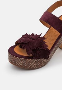 Sandale femme à plateforme à bout ouvert avec décoration fleur en daim bordeaux, bride à la cheville et talon compensé texturé multicolore.