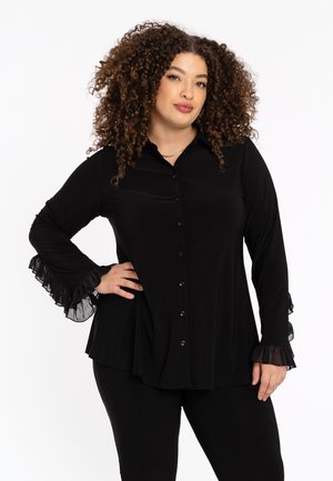 Schwarze Bluse mit Knopfleiste, langen Ärmeln und rüschigen, transparenten Akzenten an den Bündchen. Hergestellt aus einem glatten Stoff mit fließendem Design.