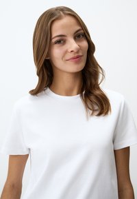 T-shirt bianca in cotone con scollatura rotonda e maniche corte. Tessuto liscio, vestibilità dritta e dettagli di design minimi.