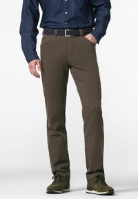 Brune chinos lavet af bomuld, med en slim fit, forlommer, og parret med en marineblå skjorte med knapper og mørkegrønne sneakers.