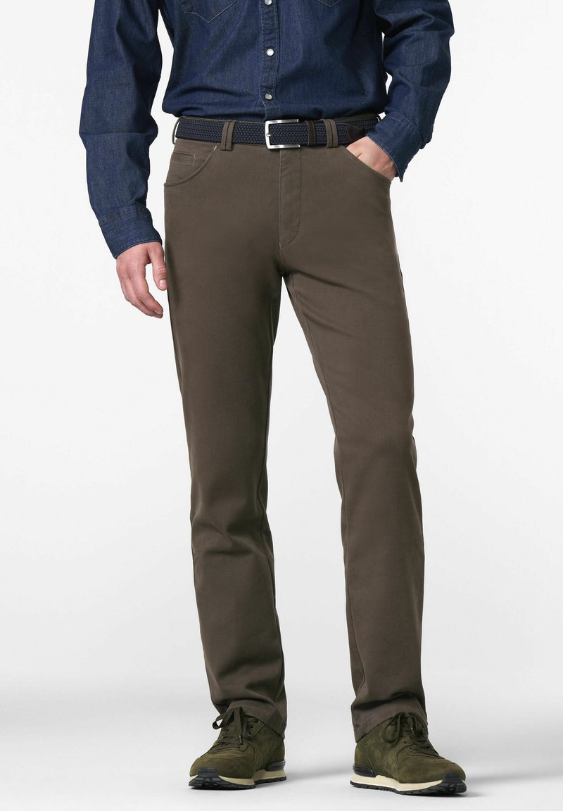 Brune chinos lavet af bomuld, med en slim fit, forlommer, og parret med en marineblå skjorte med knapper og mørkegrønne sneakers.