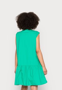 Vestido turquesa acampanado con mangas cortas, que presenta una cintura fruncida y una textura suave y lisa. Diseño simple, sin patrones ni acentos visibles.