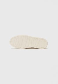 Weiße Sneakersohle aus strukturiertem Gummi, mit erhabenen Buchstaben "EXCHANGE" und glattem Rand. Minimalistisches Design ohne zusätzliche Muster.