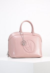 Różowa torebka z lakierowanej skóry w zaokrąglonym kształcie, z wyraźnym wytłoczonym logo oraz srebrnym łańcuchem z zawieszką z logo.