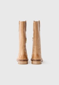 Brune lær ankle boots med en glat overflade, sidelukninger og en stablet træ hæl. Har en rund tå og let syningsdetaljer.