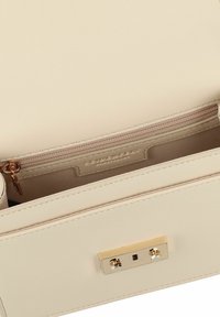 Cremefarbene strukturierte Handtasche mit einer strukturierten Außenseite, goldenen Beschlägen, einer Reißverschlusstasche und einem glatten Innenfutter.
