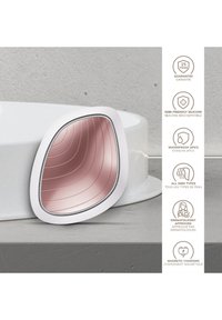 Siliconen apparaat met een gebogen wit frame en een roze reflecterende oppervlakte met groeven. Toont informatie op het oppervlak en opladen.