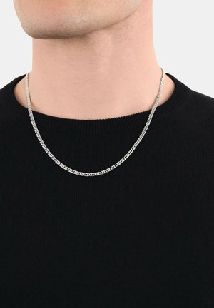 Collana in argento con link intrecciati indossata da una persona in un maglione nero a girocollo su uno sfondo semplice.
