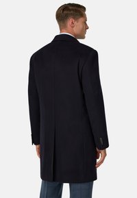 Námornícky vlněný kabát s dlouhým designem, klopový límec a jedním rozparkom vzadu. Obsahuje knoflíkové manžety a elegantní střih.