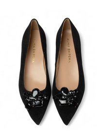 Ballerine in suede nero con punta affusolata, caratterizzate da un decorativo gruppo di gemme nere sulla parte anteriore. Logo dorato sulla soletta.