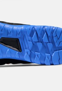 Sko sula med ett blått gummimönster, geometriska former och svarta accenter. Texturerad yta för grepp och hållbarhet.