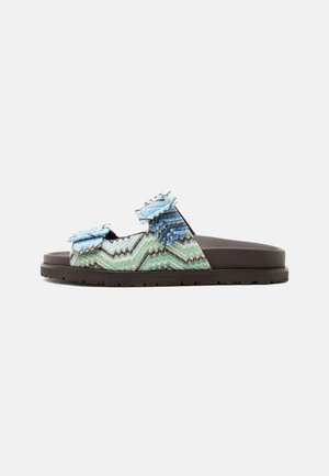 Slide sandal with two adjustable blue-green zigzag patterned fabric straps and a thick dark brown sole.