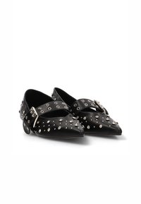 Bailarinas de cuero negro con punta afilada, que presentan tachuelas plateadas y un hebilla ajustable en la parte superior, textura suave y aberturas decorativas.