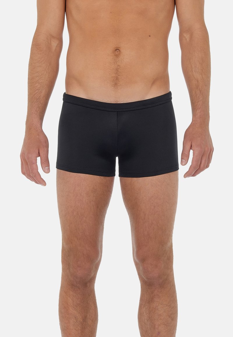 Svarta boxerkalsonger med en slät yta, elastisk midjeband och kort längd, med minimala sömmar för en slimmad passform.