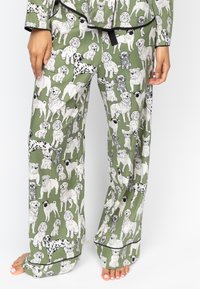 Groene pyjamabroek met een full-color print van verschillende hondenrassen in zwart en wit. Zachte stof, wijde pijpen en contrasterende bies.