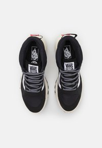 Black high-top sneakers featuring a mix of fabric and synthetic materials, white accents, black and white patterned laces, and a chunky sole.