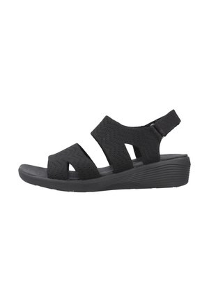 Sandalia negra con un diseño de tira trenzada, punta abierta y una suela de plataforma acolchada. Correa trasera ajustable para un ajuste seguro.