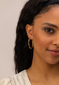 Goldfarbene, verdrehte Creolen aus Metall mit glänzender Oberfläche und einem runden, strukturierten Design.