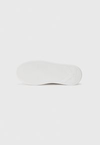 White rubber shoe sole featuring a wave pattern and a textured surface. The design includes a subtle logo and smooth edges.