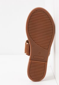 Semelle en caoutchouc d'une sandale marron avec une semelle antidérapante texturée, taille 37 indiquée, et une bride latérale visible avec des détails tissés.
