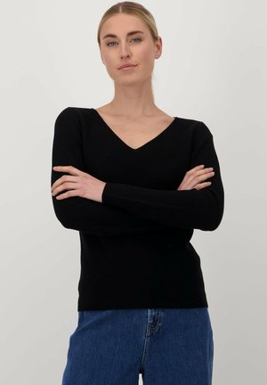 Zwarte gebreide trui met een V-hals, getailleerde snit, lange mouwen en een zachte textuur, gecombineerd met blauwe jeans.