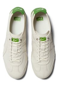 Białe skórzane sneakersy z zielonymi akcentami. Posiadają okrągły czubek, płaskie sznurowadła i teksturowaną podeszwę. Logo widoczne na języku i pięcie.