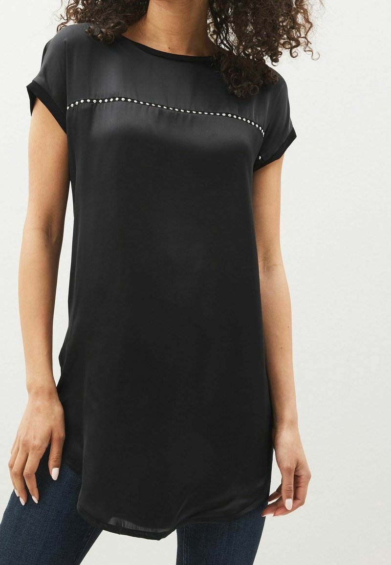 Sort silken blouse med korte ærmer, der har en vandret række af dekorative nitter over brystet. Glat tekstur og afslappet pasform.