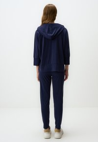 Felpa con cappuccio blu navy con maniche a tre quarti e pantaloni abbinati, realizzata in tessuto morbido, con una vestibilità rilassata e un design minimal.