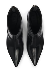 Bottes de cheville en cuir noir avec un bout pointu, texture lisse et fermeture éclair. L'intérieur est en tissu sombre sans marque visible.