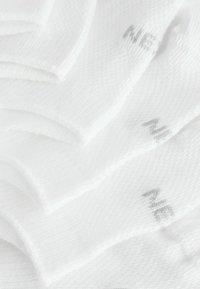 White cotton socks with a ribbed texture, featuring light gray branding. Multiple pairs are stacked in a slightly overlapping arrangement.