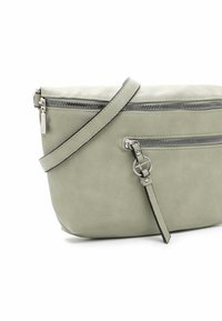 Sac bandoulière en cuir vert clair avec plusieurs compartiments zippés et une sangle réglable. Texture lisse avec des accents en métal argenté.