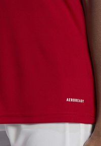 Rotes Sport-T-Shirt aus atmungsaktivem Material, mit glatter Textur und einem auffälligen "AEROREADY"-Logo in Weiß nahe dem Saum.