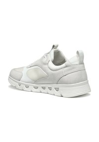 Zapatilla blanca con una mezcla de materiales lisos y texturizados, que cuenta con una puntera redondeada, suela gruesa y acentos de diseño minimalistas.
