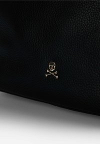 Musta teksturoitu nahkabagi, jossa on kultainen pääkallo ja ristiluut-embleemi. Materiaalissa on nappapintainen viimeistely, joka lisää visuaalista kiinnostavuutta.